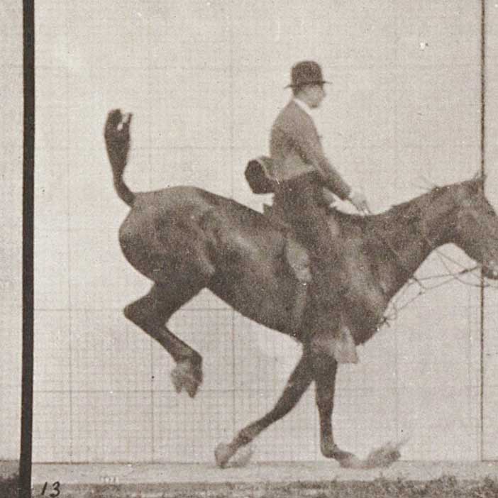 A gentleman wearing a top hat gracefully rides a racing horse